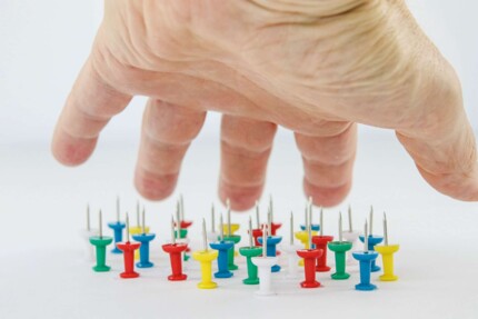 Eine ausgestreckte Hand wird oberhalb aufgerichteter Nadeln gehalten ohne diese zu berühren