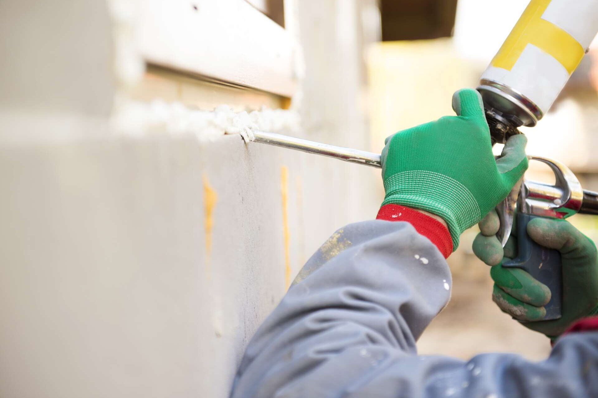 Mann, der Schaumversiegelungsmittel mit Abdichtungspistole aufträgt, um das Fenster zu isolieren