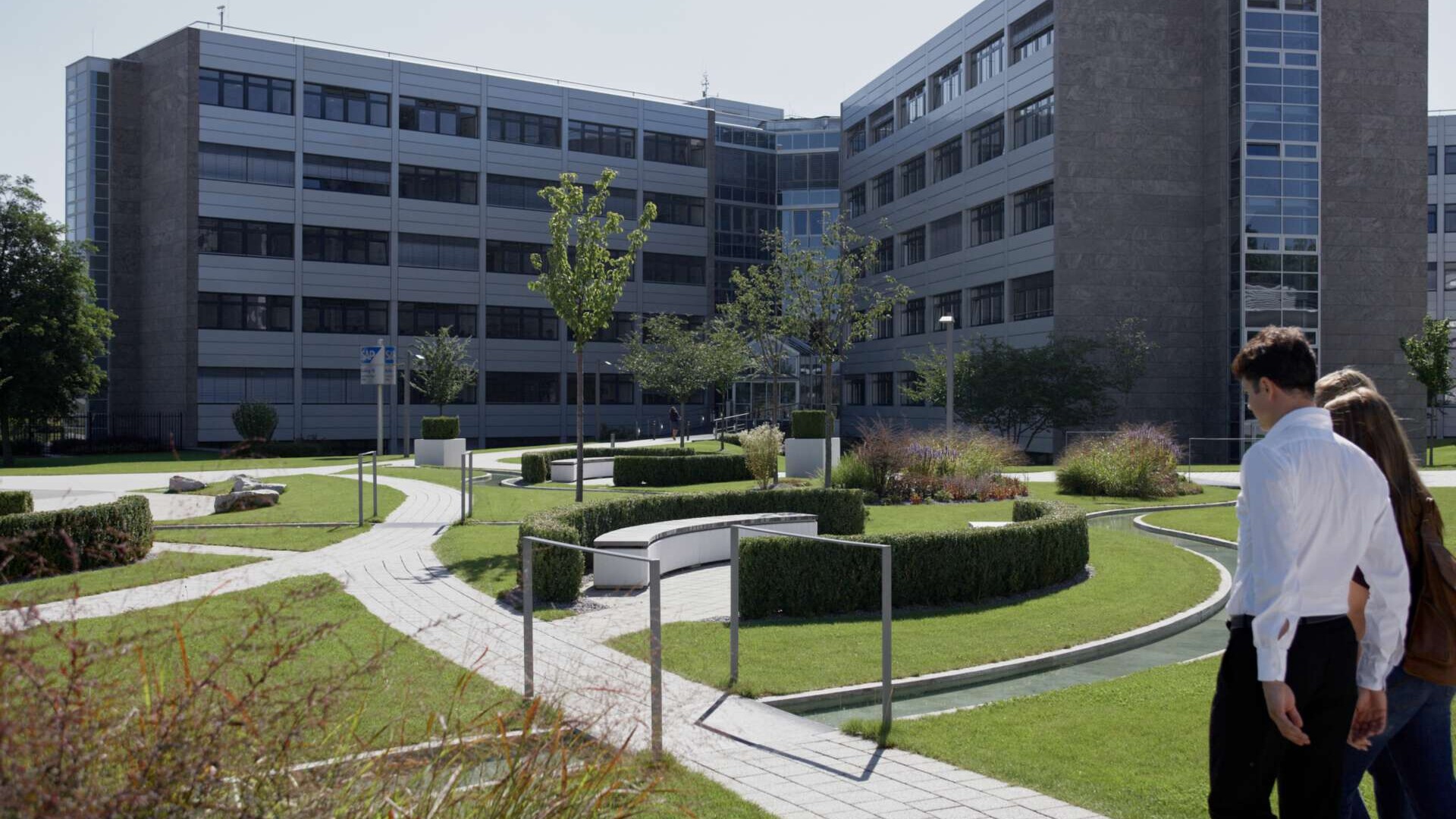 Büroangestellte in einem Park vor einem Bürogebäude