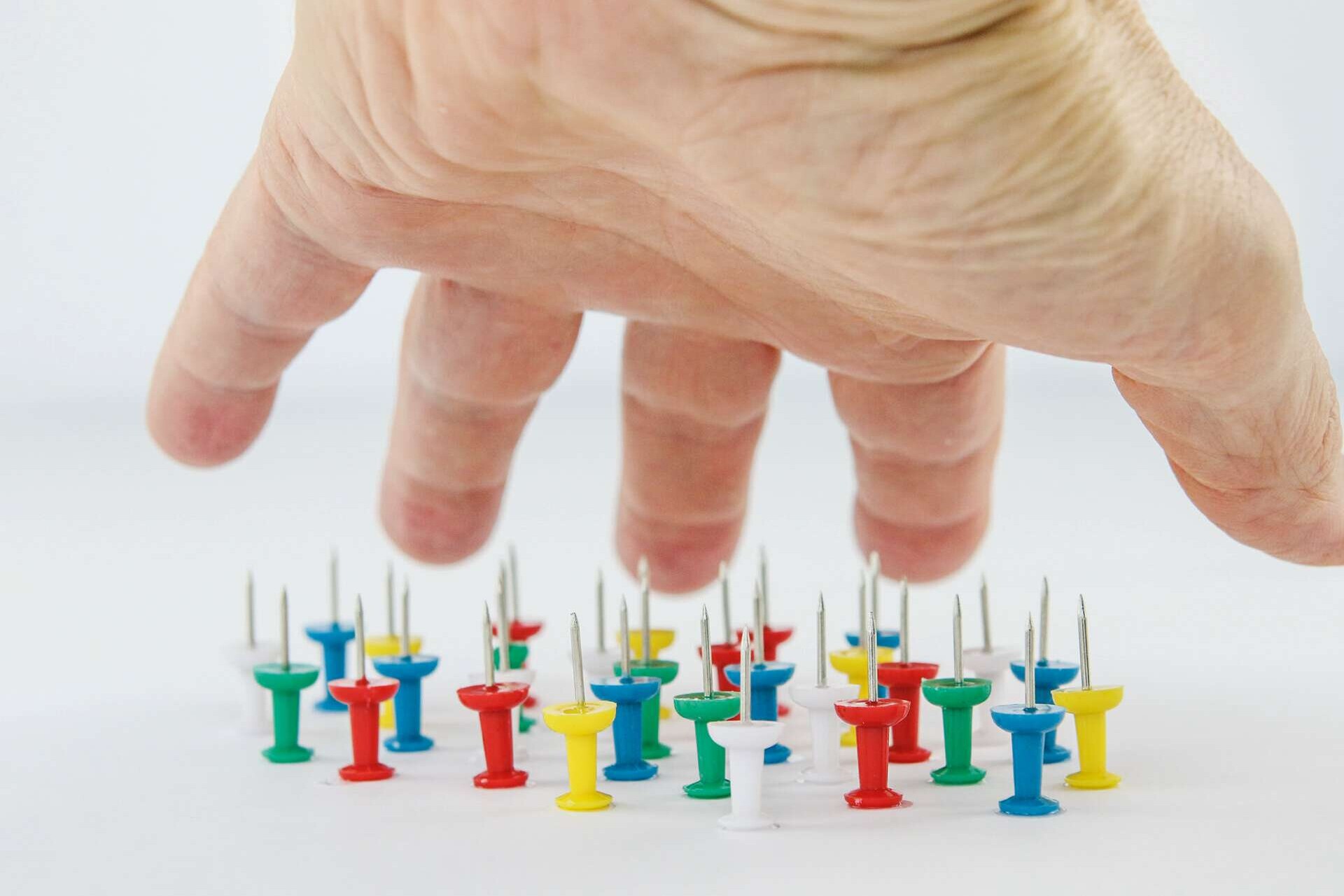 Eine ausgestreckte Hand wird oberhalb aufgerichteter Nadeln gehalten ohne diese zu berühren