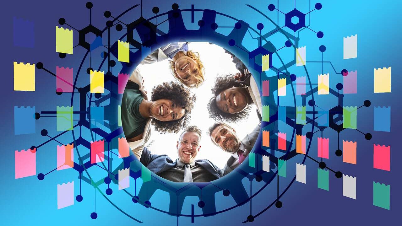 Menschen schauen in eine virtuelle Umgebung, die aussieht wie ein Zahnrad das durch bunte Vierecke überlagert ist