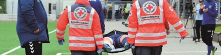 Sanitäter tragen einen verletzen Fußballer auf einer Trage