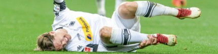 Verletzter Fußballspieler (Jannik Vestergaard) liegt mit schmerzverzerrtem Gesicht auf dem Spielfeld.