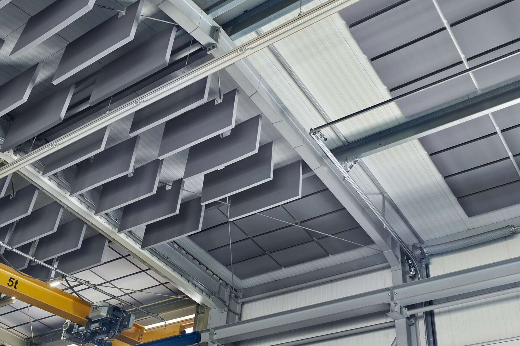 Die Decke einer Industriehalle wurde mit liegenden und hängenden schallabsorbierenden Deckenelementen ausgestattet.