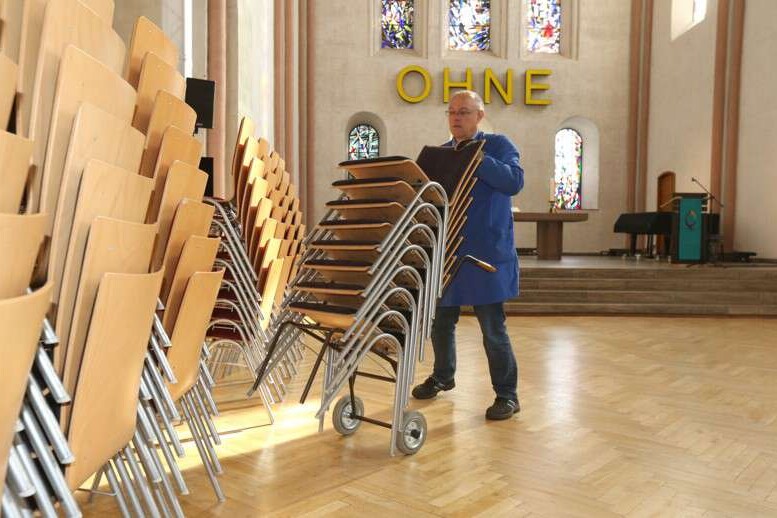 Ein Mann schiebt Stühle in der Kirche