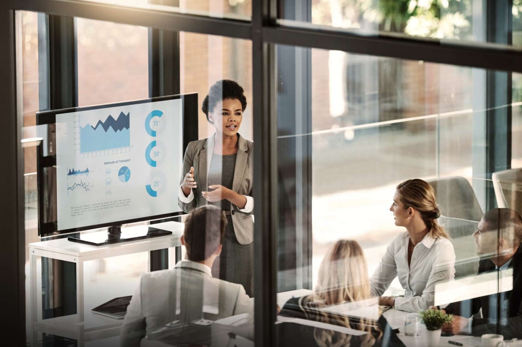 Frau präsentiert Statistik vor einer Gruppe am Tisch